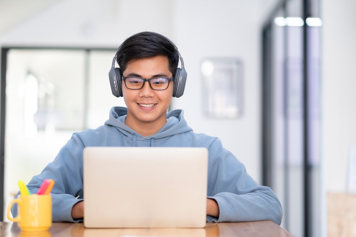 Young collage student using computer and mobile device studying online.